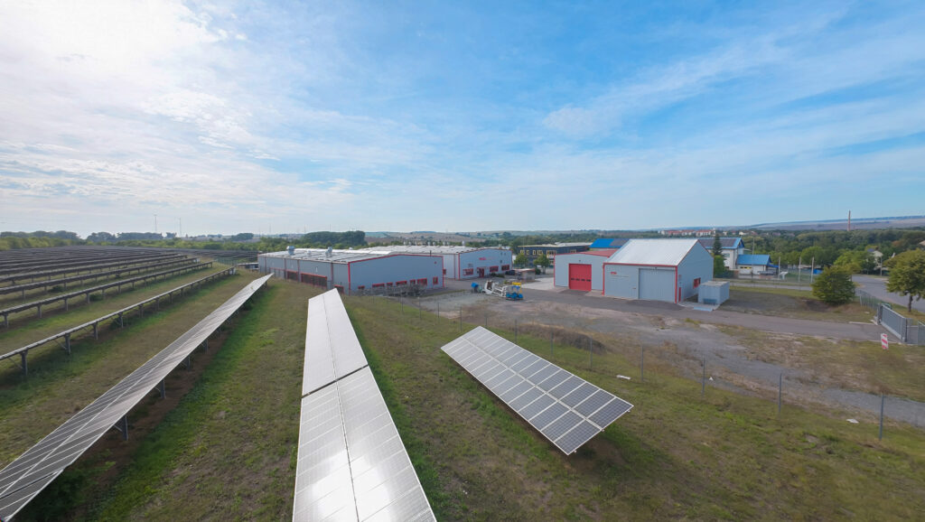 Freifeld-Solaranlage im Vordergrund, die PECO Schaum GmbH im Hintergrund